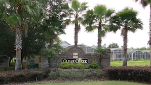 A sign for Clear Creek with a brick archway and palm trees in the foreground. - Clear Creek 909 (Clermont)
