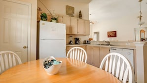 A compact kitchen with white cabinets, a refrigerator, and a dining table with chairs. - Clear Creek 909 (Clermont)