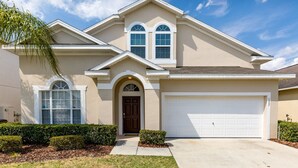 Une maison de plain-pied à l’extérieur beige, avec une porte d’entrée marron et une porte de garage blanche.