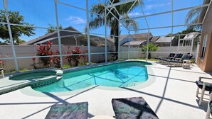 Uma piscina com área de sombra e espreguiçadeiras.