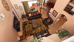 Uma sala de estar ampla com ventilador de teto, um conjunto de sofás, uma mesa de centro e uma área de jantar com cadeiras e mesa.