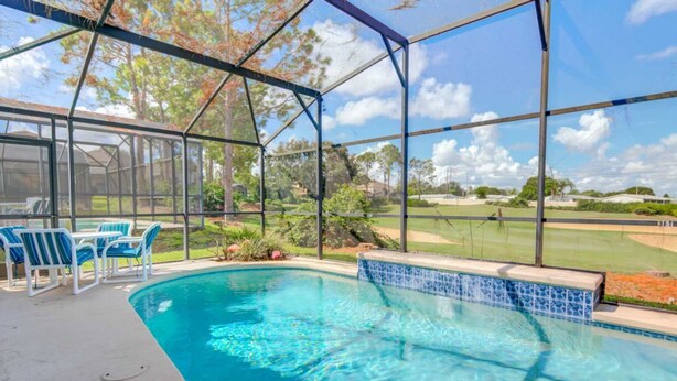 Piscina com área coberta, borda azulejada em azul e vista para um campo de golfe.