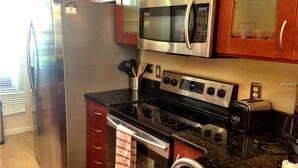 A kitchen with stainless steel appliances, including a refrigerator, microwave, stove, and toaster.