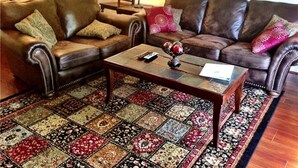 A living room with two leather sofas, a coffee table, and a patterned rug.