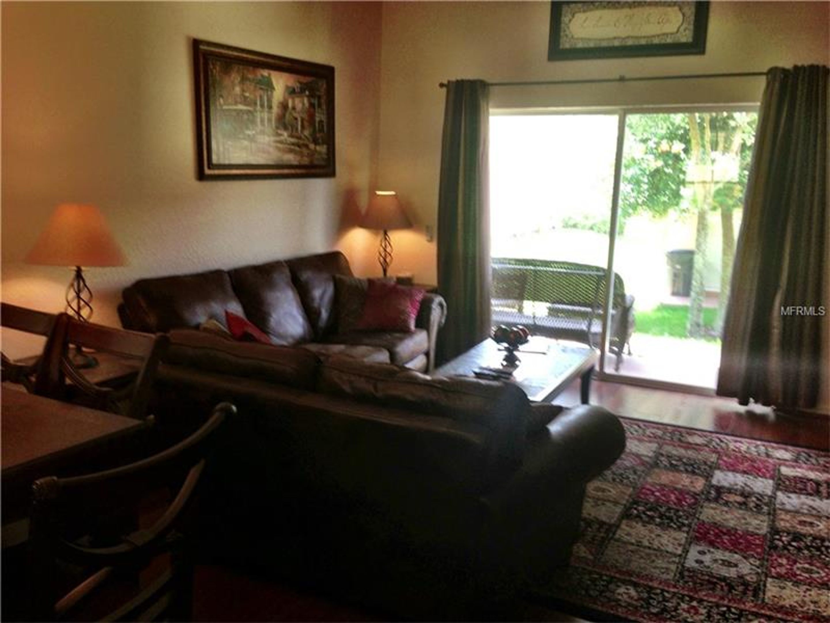 A living room with a leather sofa, two lamps, a table, and a patterned rug.
