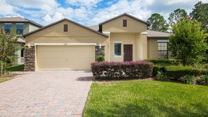 A two-story house with a beige garage door, a stone facade, and a well-maintained lawn. - Cypress Pointe 1097 (Davenport)
