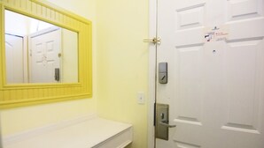 Un bany amb un mirall de marc groc, un lavabo blanc i una porta blanca amb pany i un senyal.