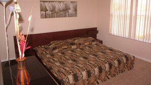 A bedroom with a bed, a nightstand, a vase with flowers, a ceiling fan, and a window with blinds. - Regal Palms Resort & Spa 124 (Davenport)