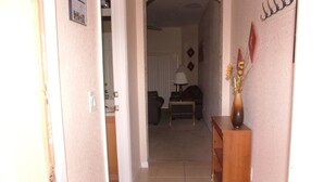 A hallway leading to a living room with a sofa, a lamp, and a vase with flowers on a side table. - Regal Palms Resort & Spa 124 (Davenport)