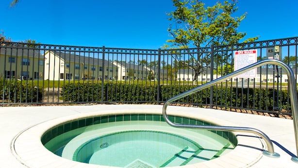 A hot tub surrounded by a metal fence, with a sign indicating spa services. - Club Cortile 2730b (Kissimmee)