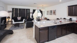 A modern kitchen with dark cabinetry, a granite countertop, and a dishwasher. - Compass Bay 3131 (Kissimmee)