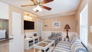Una sala de estar con ventilador de techo, televisor, sofá y una mesa de centro.