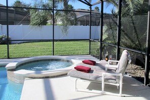 A hot tub with two lounge chairs and a bottle of champagne.