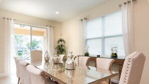 A dining area with a glass table, beige chairs, and a potted plant. - Encore Resort at Reunion 641 (Kissimmee)