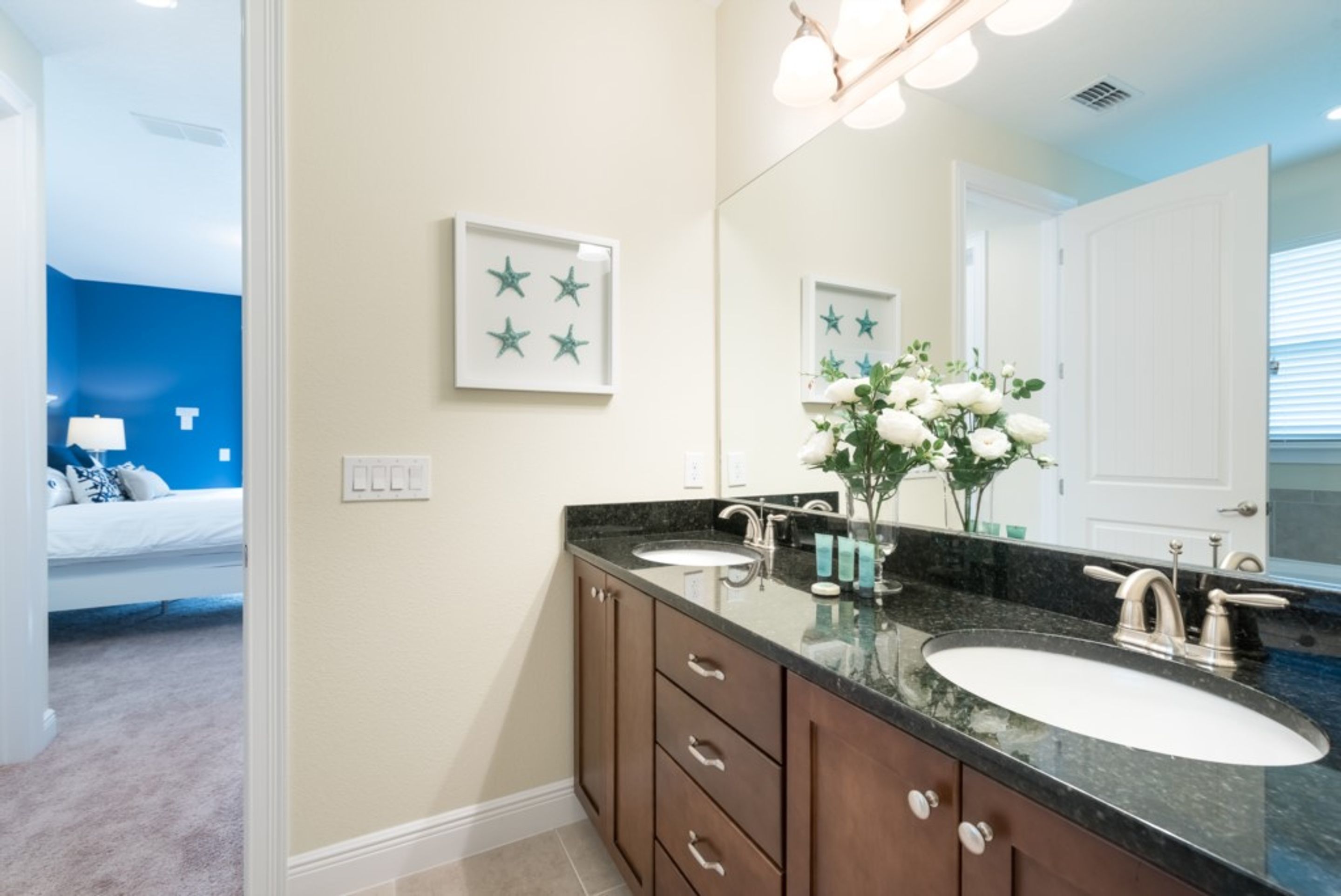 A bathroom with a double sink vanity, a large mirror, and a wall-mounted star decoration.