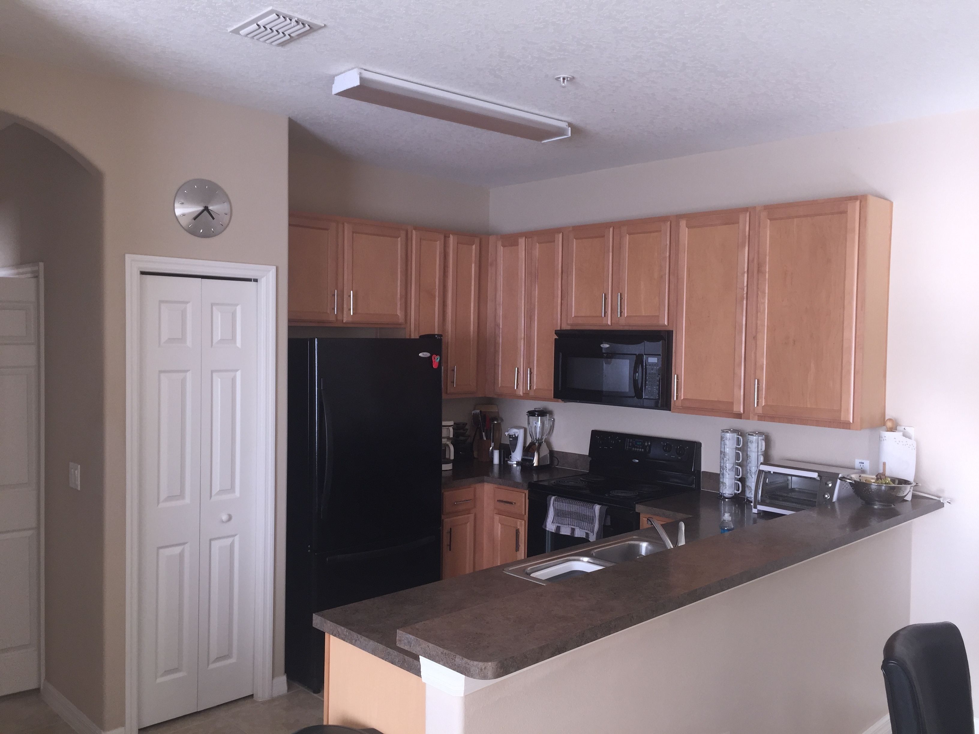 A kitchen with wooden cabinets, a black refrigerator, a microwave, a stove, and a sink.