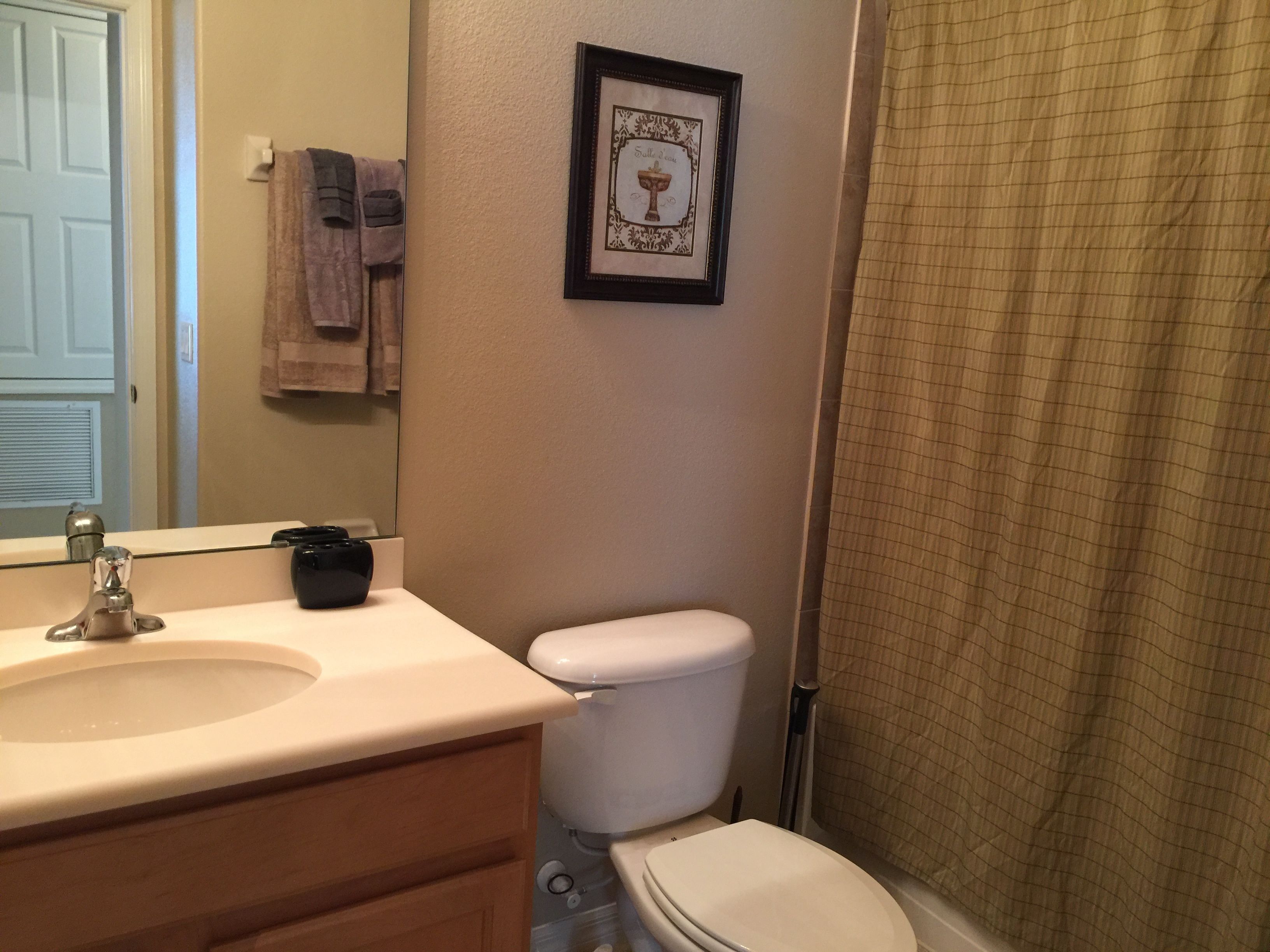 A bathroom with a sink, toilet, and a framed picture on the wall.