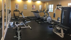 Un gimnasio con cintas de correr, elípticas y equipo de levantamiento de pesas.