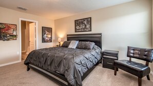 A bedroom with a large bed, bedside tables, a chair, and wall art. - Cypress Pointe 1132 (Davenport)