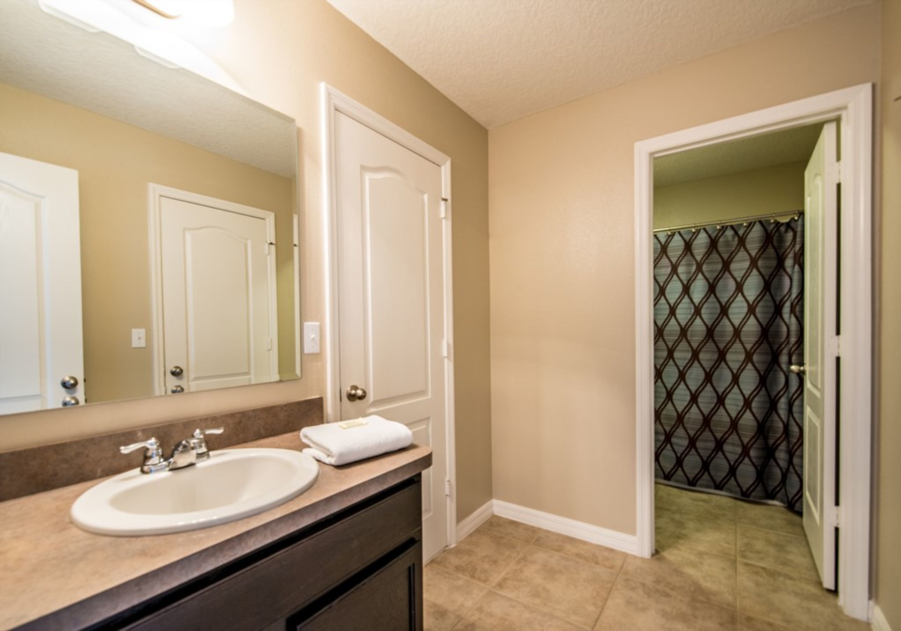A bathroom with a sink, mirror, and towel.