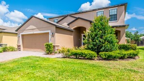 A two-story house with a garage, a well-maintained lawn, and a large tree in front. - Cypress Pointe 1132 (Davenport)
