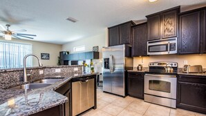 A modern kitchen with granite countertops, stainless steel appliances, and dark wooden cabinets. - Cypress Pointe 1132 (Davenport)