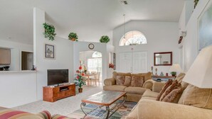 A living room with a sofa, a TV, a coffee table, and a dining area with a table and chairs. - Southern Dunes 2224 (Haines City)