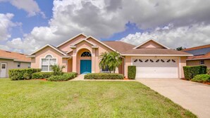 A two-story house with a blue front door, a garage, and a well-maintained lawn. - Southern Dunes 2224 (Haines City)