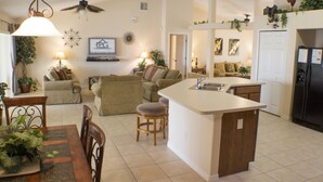 A spacious living area with a kitchen island, a dining table with chairs, and a ceiling fan. - Legacy Park The Estates 247 (Davenport)