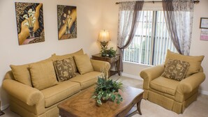 A living room with a beige sofa set, a wooden coffee table, and a side table with a lamp. - Legacy Park The Estates 247 (Davenport)