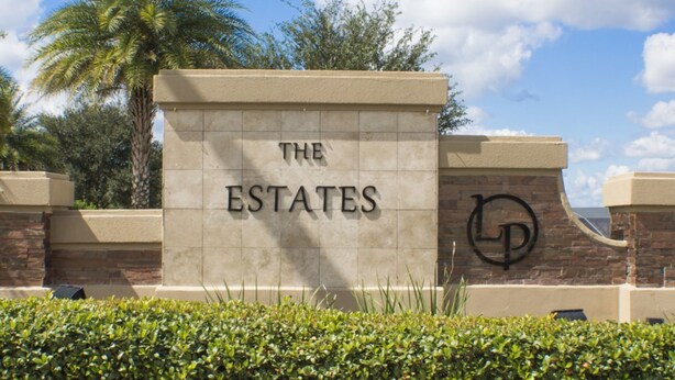 A sign with "THE ESTATES" and a logo, surrounded by greenery and a palm tree. - Legacy Park The Estates 247 (Davenport)