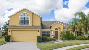 A two-story house with a yellow facade, a garage, and a well-maintained lawn. - Legacy Park The Estates 247 (Davenport)