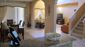 A living room with a dining area, a staircase, and a TV in the background. - Crystal Cove 4730 (Kissimmee)