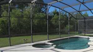A covered swimming pool with a hot tub, surrounded by a fence and trees. - Crystal Cove 4730 (Kissimmee)