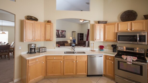 A modern kitchen with wooden cabinets, stainless steel appliances, and a dishwasher. - The Hamlet at Westhaven 320 (Davenport)