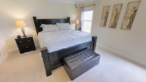 A bedroom with a large bed, a nightstand, a lamp, and artwork on the wall. - Paradise Palms 8876 (Kissimmee)