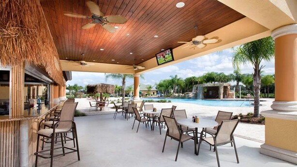 An outdoor patio area with seating and a pool. - Paradise Palms 8876 (Kissimmee)