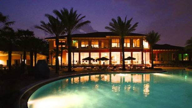 A hotel with a swimming pool, palm trees, and outdoor seating areas.