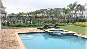 Une piscine bordée de briques et un espace dédié à un jacuzzi.