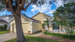 A residential house with a garage, a large tree in the front yard, and a well-maintained lawn. - Highlands Reserve Golf & Country Club 104 (Davenport)
