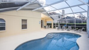 An indoor swimming pool with a glass ceiling, surrounded by lounge chairs and a beige building. - Highlands Reserve Golf & Country Club 104 (Davenport)