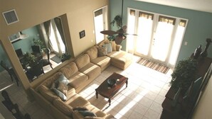 Uma sala de estar com um sofá seccional bege, uma mesa de centro de madeira e um espelho grande na parede.