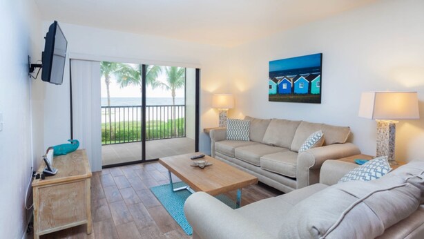 A modern living room with a sofa, coffee table, and a TV mounted on the wall.