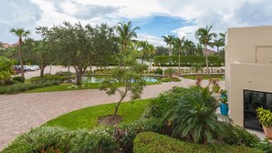 A landscaped courtyard with a pool, palm trees, and a paved walkway.