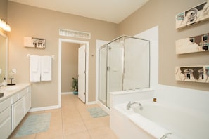 A modern bathroom with a glass-enclosed shower, a large bathtub, and a vanity with a mirror.