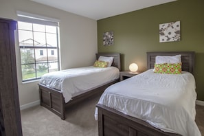 A bedroom with two beds, a window, and a nightstand with a lamp. - Champions Gate 9027 A (Davenport)