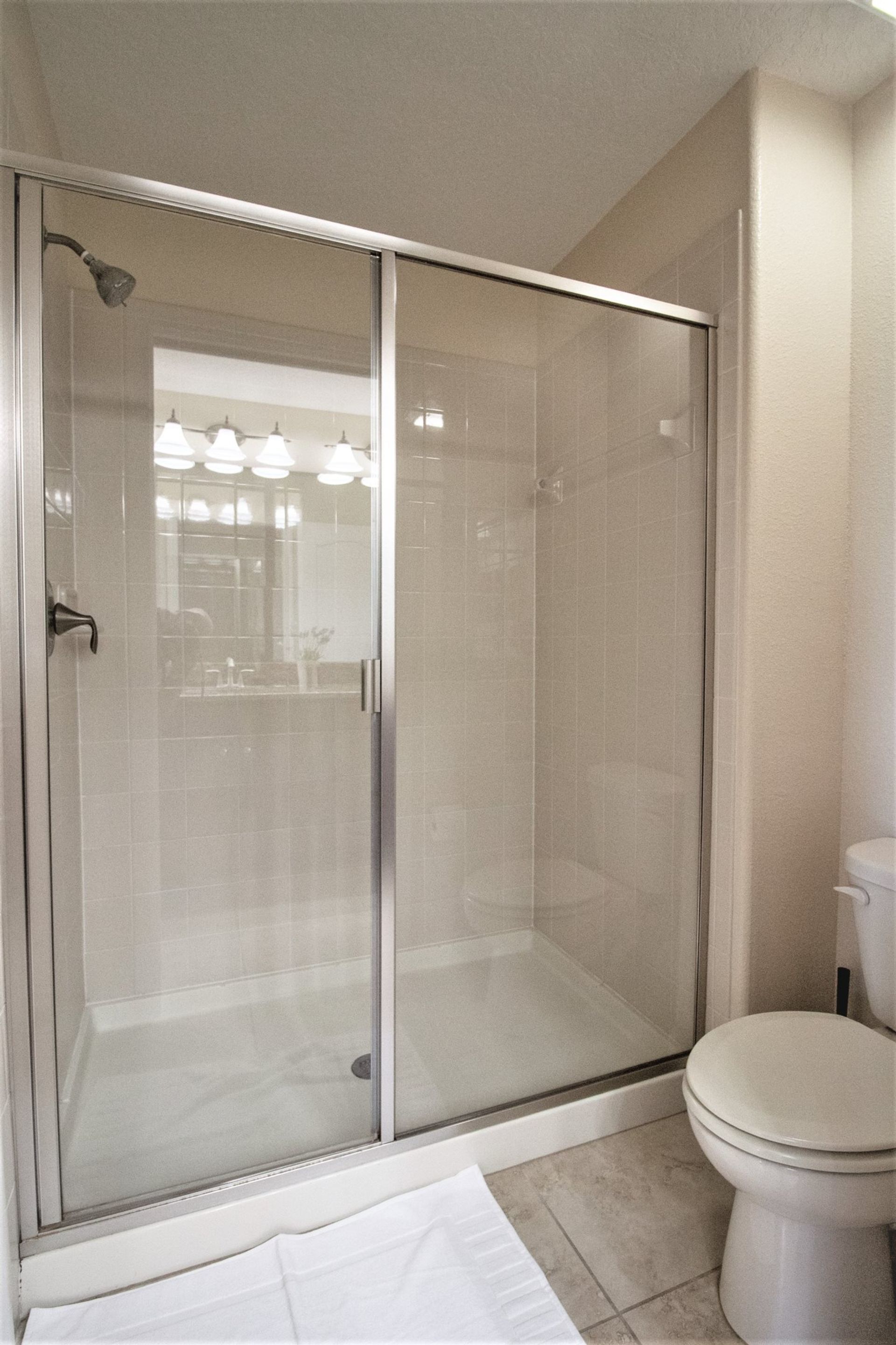 Une salle de bain moderne dotée d’une douche à parois de verre, de toilettes et d’un lavabo.