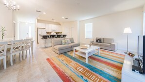 A modern living room with a sofa, coffee table, and a dining area with chairs and a table. - Bella Vida 871 (Kissimmee)