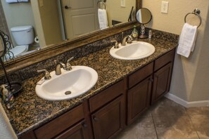 A bathroom with two sinks, a large mirror, and wooden cabinets. - Bella Piazza 904 - 511 (Davenport)