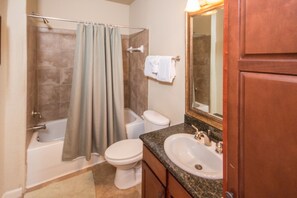 A bathroom with a bathtub, toilet, sink, and a mirror above the sink.